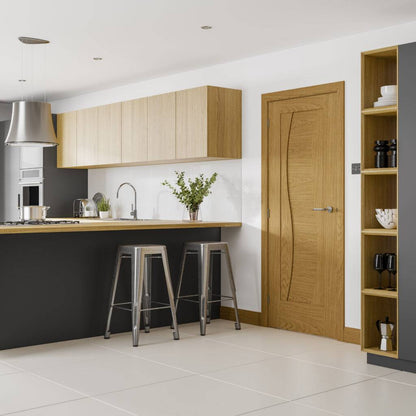 Modern kitchen with wooden cabinets, a door, and bar stools.